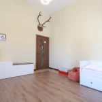 miegamasis su aukštomis lubomis ir medinėmis grindimis